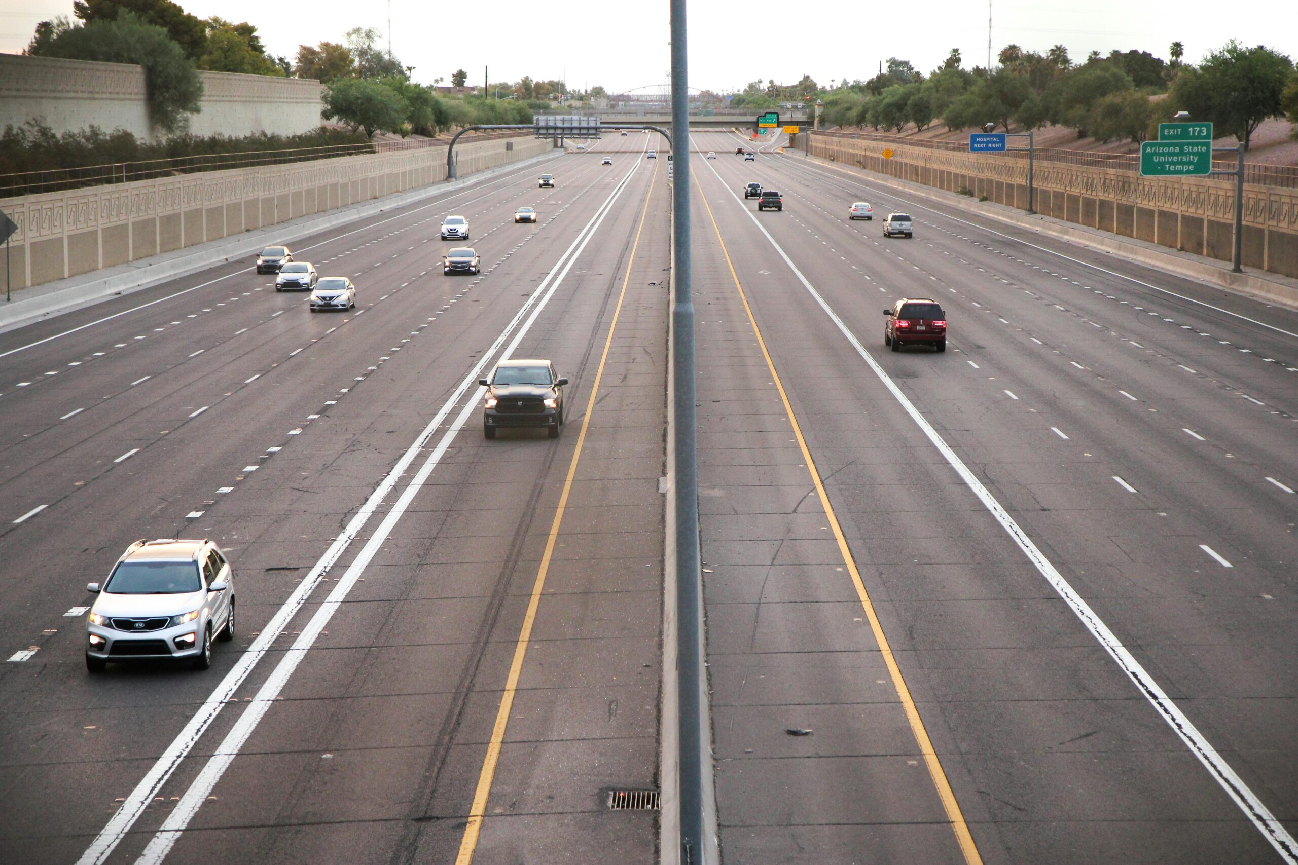 Aerial view of a deserted highway with few cars during dusk, depicting calm traffic conditions.